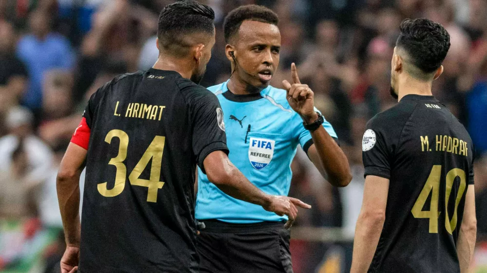 Referee Omar Artan, center, of Somalia, is confronted by players after calling a penalty kick during the CAF Champions League final soccer match between AS FAR Rabat and Mamelodi Sundowns, in Rabat, Morocco, Sunday, May 24, 2026. (AP Photo/Mosa'ab Elshamy)