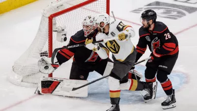 Carolina Hurricanes' Brandon Bussi (32) reaches for the puck ahead of Sean Walker (26) as Vegas Golden Knights' Colton Sissons (10) attempts a shot during the third period of Game 5 of the NHL hockey Stanley Cup Final series in Raleigh, N.C., Thursday, June 11, 2026. (AP Photo/Ben McKeown)