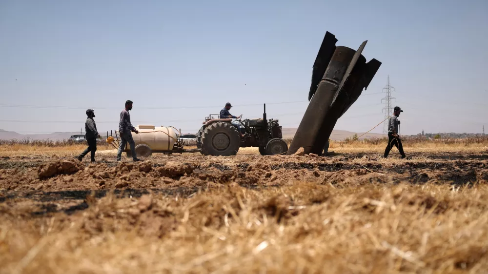 Farmers spray water in a burned agricultural field next to a projectile near the town of Najha, Syria, Monday, June 8, 2026, after debris from Iranian missile launches during the Iran-Israel conflict fell in the area. (AP Photo/Ghaith Alsayed)