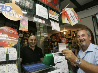 An unidentified man, right, shows his SuperEnalotto lottery ticket at a betting center in Castel Gandolfo, on the outskirts of Rome, Wednesday, Aug. 12, 2009. The record jackpot for Italy's state lottery increased to euro 131.5 million (6.2 million) after the latest drawing Tuesday again thwarted those hoping to get the winning, six-number combination. No one has hit the jackpot in the SuperEnalotto game since January, causing the prize to increase to the highest level in Italy's and Europe's history. The next drawing is Thursday. (AP Photo/Pier Paolo Cito)