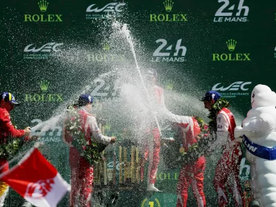 The 24 Hours of Le Mans - Circuit de la Sarthe, Le Mans, France - June 14, 2026 Toyota Racing's Mike Conway, Kamui Kobayashi, and Nyck de Vries celebrate on the podium with champagne and team members after winning the 24 Hours of Le Mans REUTERS/Stephane Mahe