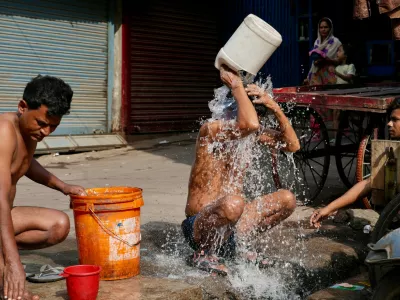 Indian rickshaw driver bathes from a roadside water tap during a hot summer day in Lucknow, northern Indian state of Utter Pradesh, Monday, June 15, 2026. (AP Photo/Rajesh Kumar Singh)