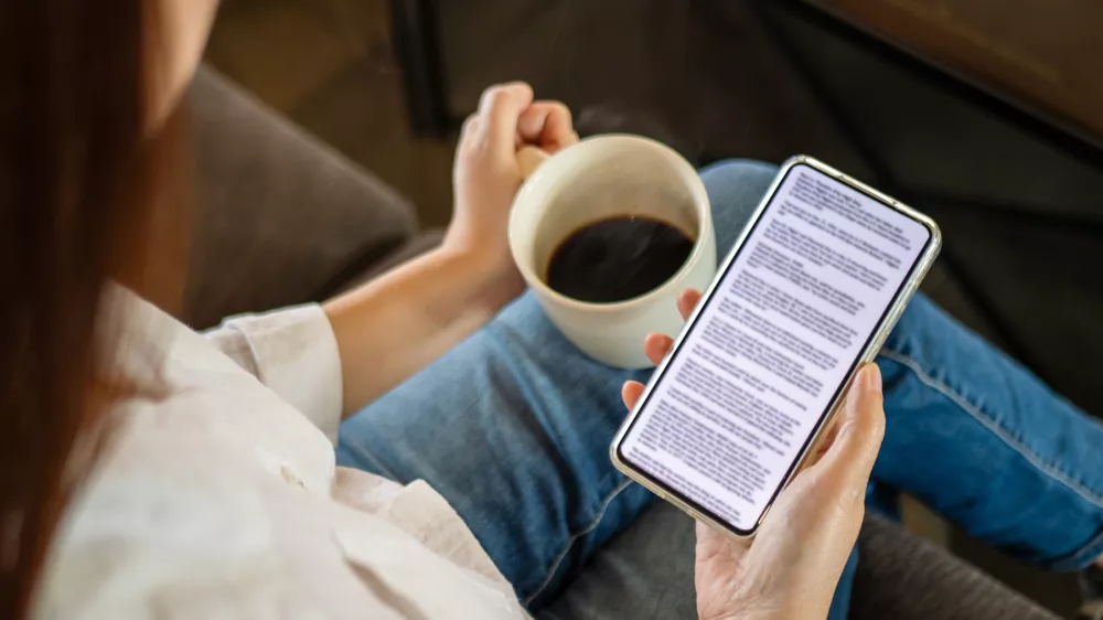 woman hand holding coffee cup and phone, reading text on mobile screen for digital press article feed in the morning. mockup media publication website in smartphone.