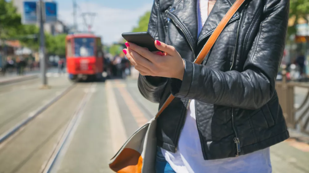 Using cellphone with defocused city tram.