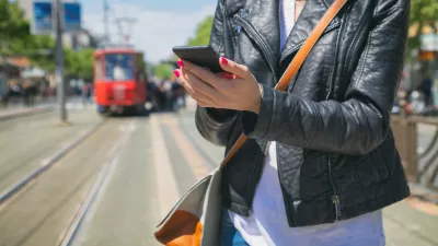 Using cellphone with defocused city tram.