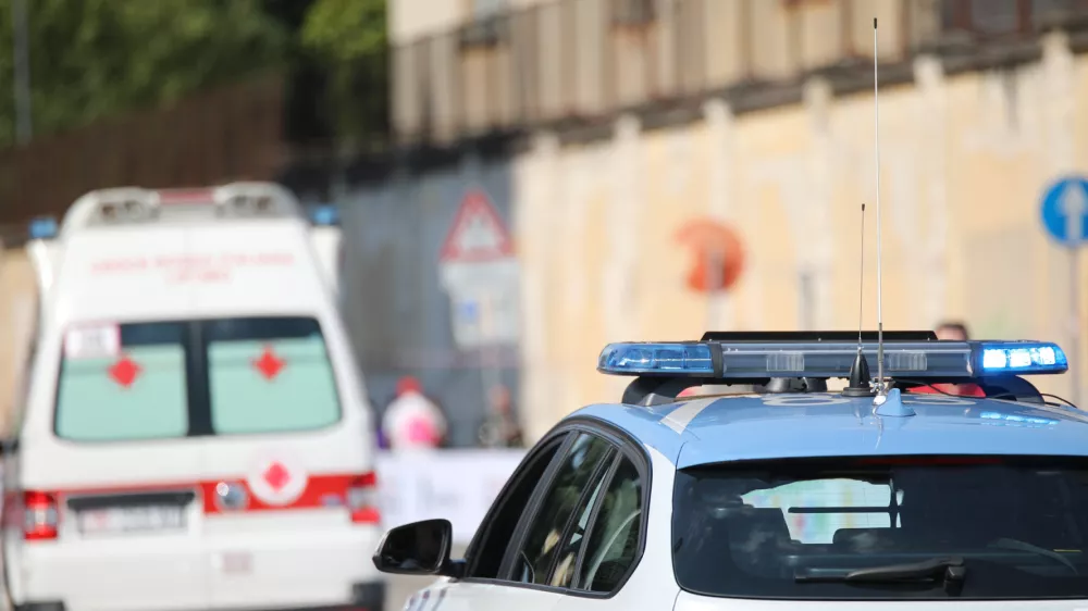 police car with blue flashing lights on it while escorting an ambulance to go to the hospital after the accident