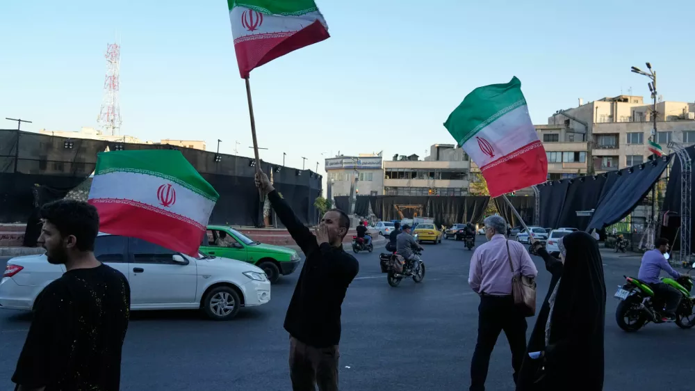 Demonstrators wave Iranian flags as they chant slogans against Iran and U.S. talks at the Islamic Revolution square in Tehran, Iran, Sunday, June 14, 2026. (AP Photo/Vahid Salemi)