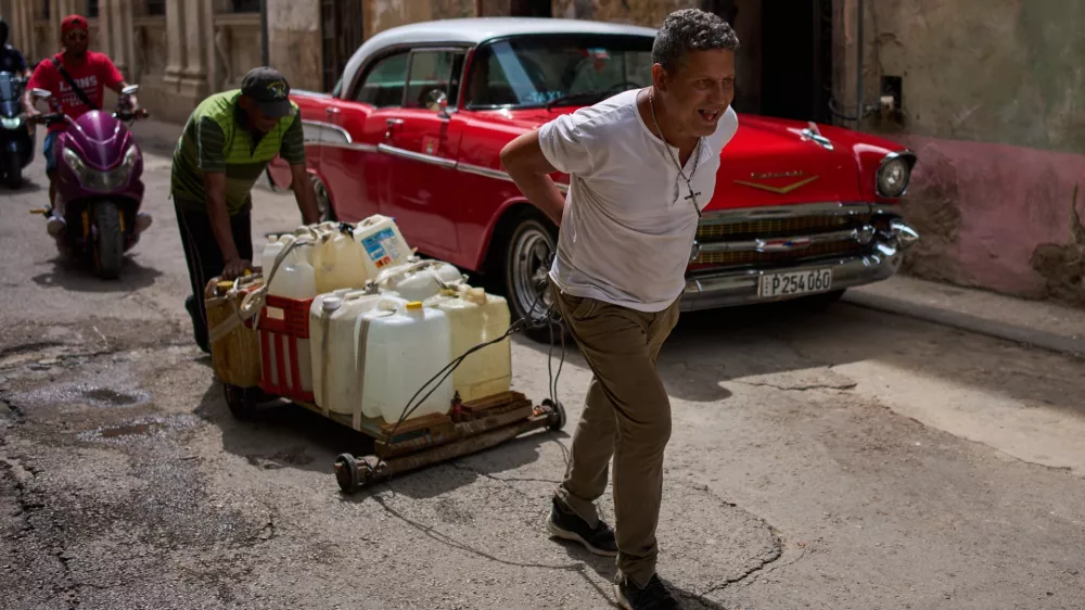 People transport containers of water in Havana, Wednesday, June 3, 2026. (AP Photo/Ramon Espinosa)
