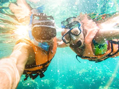 Senior happy couple taking selfie in tropical sea excursion with water camera - Boat trip snorkeling in exotic scenarios - Active retired elderly and fun concept on scuba diving - Warm vivid filter / Foto: Viewapart