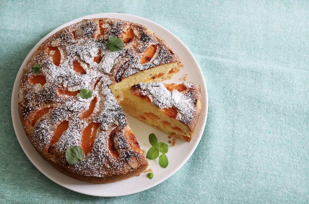 Delicious homemade apricot cake decorated with fresh mint leaves. Summer dessert. Directly above. / Foto: Grazziela Bursuc