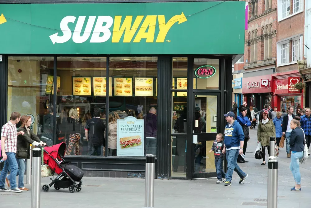 People pass by Subway sandwich shop in Liverpool. Subway has 44,280 fast food restaurants in 110 countries. / Foto: Tupungato