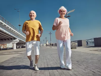 Full-length portrait of a high-spirited senior lady and her husband power walking along the quay / Foto: Yacobchuk