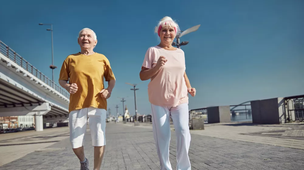 Full-length portrait of a high-spirited senior lady and her husband power walking along the quay / Foto: Yacobchuk