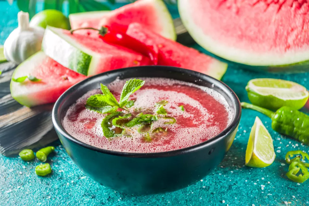 Summer cold watermelon smoothie gazpacho soup, marine blue background with watermelon slices, lime and herbs / Foto: Rimma_bondarenko