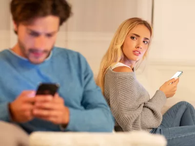 Infidelity. Wife Catching Cheating Husband Texting On Cellphone With Another Woman Sitting On Sofa At Home. Selective Focus / Foto: Prostock-studio Getty Images