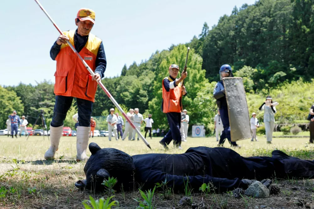 Hunters and a police officer approach a man wearing a bear costume who plays dead after a simulated hunt during an emergency drill for a bear intrusion in Yaita, Tochigi Prefecture, Japan, June 17, 2026. REUTERS/Kim Kyung-Hoon   TPX IMAGES OF THE DAY