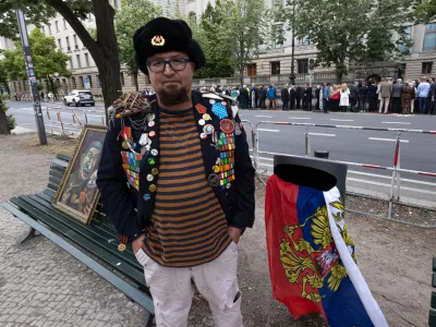 A man identified by Polish media as Robert Kuzovkov and by prosecutors as Robert K., in accordance with Polish privacy law, who they said was an artist who used the pseudonym Semyon Skrepetsky, poses for a photo with one of his paintings near the Russian Embassy in Berlin, Germany, on Friday, June 12, 2026, four days before Polish authorities said he was shot and killed in Biala Podlaska, Poland. (Vasily Krestyaninov/SOTA via AP)