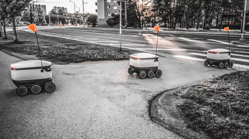 Some Delivery robots on the street. Estonian Cyber-couriers in Tallinn city. Sunny summer day. Copy space. Fitered image. the concept of new technology.