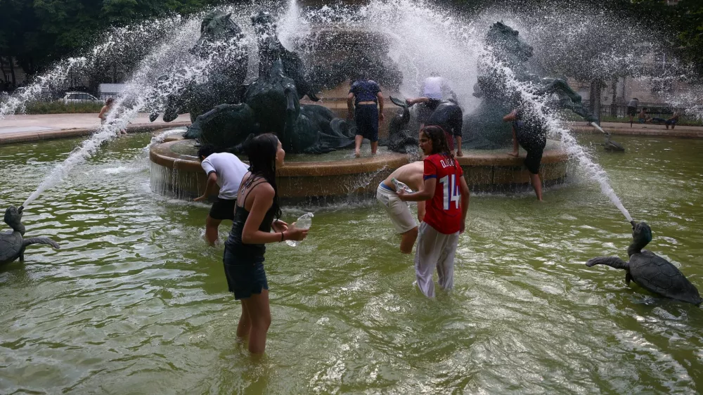 Young people cool off in the Fontaine de l'Observatoire fountain as temperatures rise in Paris and a heatwave hits a large part of France, June 18, 2026. REUTERS/Abdul Saboor