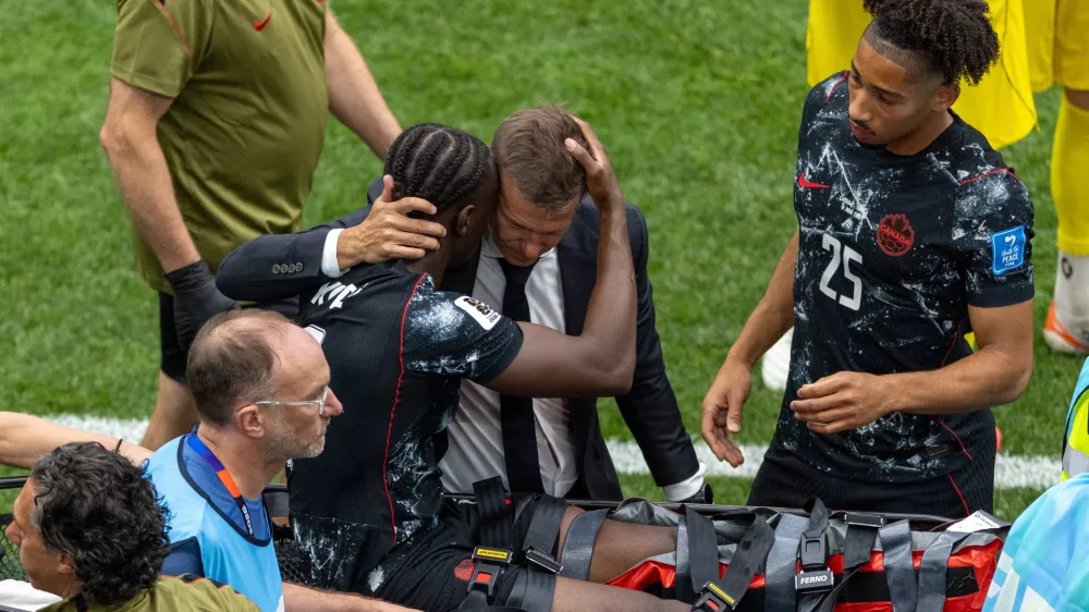 Canada head coach Jesse Marsch embraces Ismael Kone (8) as he is stretchered off the field after an injury during the World Cup Group B soccer match between Canada and Qatar in Vancouver, British Columbia, Thursday, June 18, 2026. (Timothy Matwey/The Canadian Press via AP)