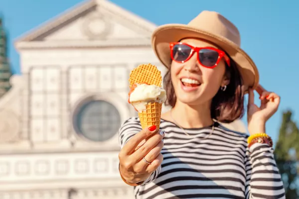 Young happy asian tourist woman eating ice-cream in front of the Croce basilica church in Florence