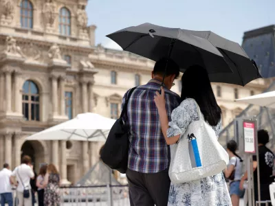 Tourists protecting themselves from the sun under umbrellas stand in front of the Pyramid of the Louvre Museum as temperatures rise in Paris during a second heatwave affecting a large of France, June 19, 2026. REUTERS/Alice Sacco