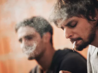 Closeup of young friends smoke pot or hashish joint in abandoned ghetto part of the city