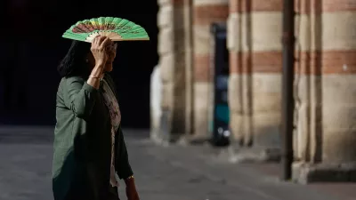 A woman holds a fan over her face to shield herself from the sun during hot weather in Bologna, Italy, June 20, 2026. REUTERS/Vincenzo Livieri