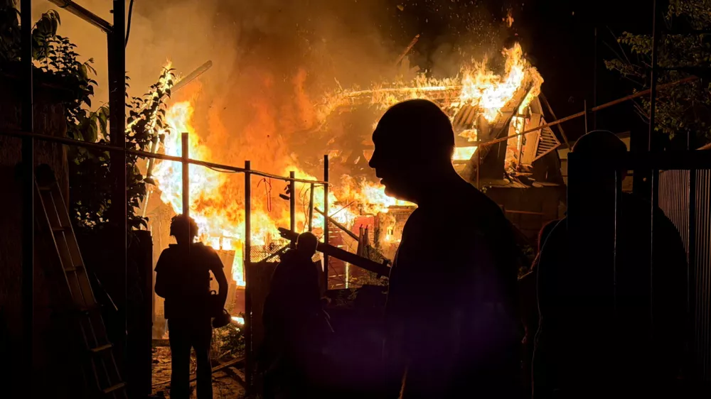 Residents look at a private house that burns after an overnight Russian drone strike, amid Russia's attack on Ukraine, in Zaporizhzhia, Ukraine June 22, 2026. Picture taken with a mobile phone. REUTERS/Serhii Chalyi   TPX IMAGES OF THE DAY