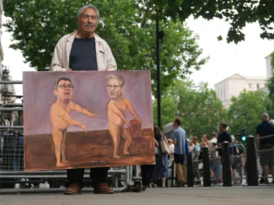 Artist Kaya Mar shows his newest painting outside Downing Street after Britain's Prime Minister Keir Starmer announced his resignation in London, Monday, June 22, 2026.(AP Photo/Alastair Grant)