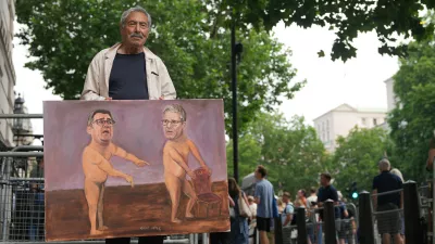 Artist Kaya Mar shows his newest painting outside Downing Street after Britain's Prime Minister Keir Starmer announced his resignation in London, Monday, June 22, 2026.(AP Photo/Alastair Grant)