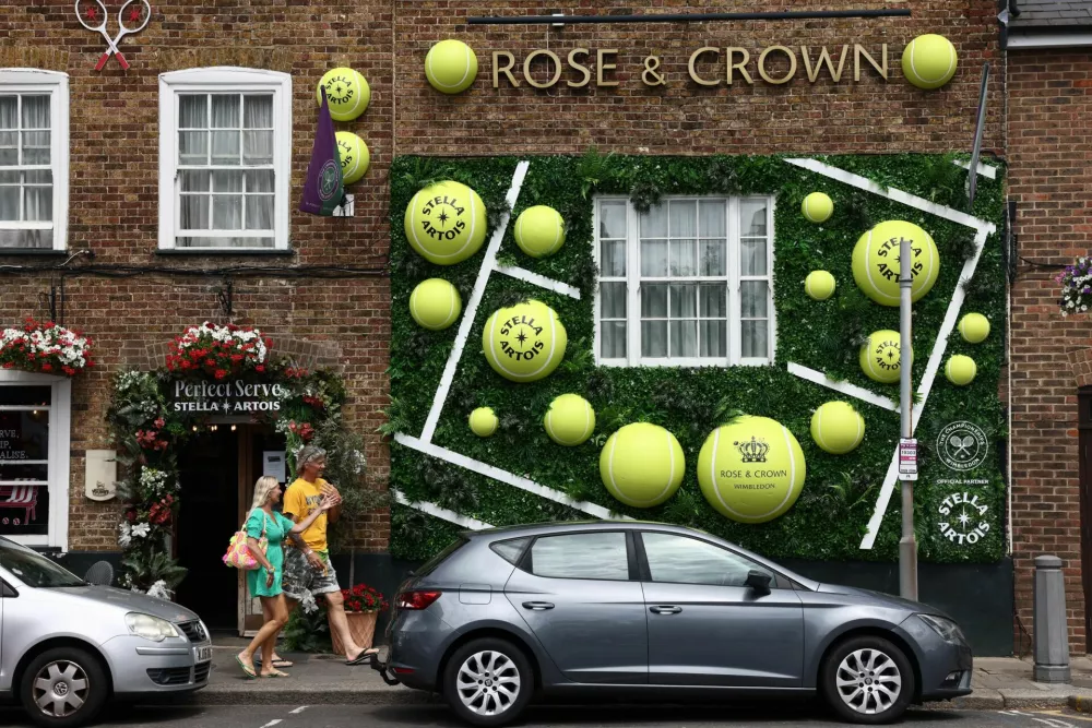 People walk past a tennis-themed display outside a pub in Wimbledon Village ahead of the first day of Wimbledon at the All England Lawn Tennis and Croquet Club, London, Britain, June 28, 2026. REUTERS/Jack Taylor
