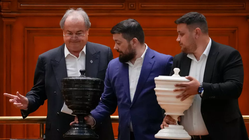 Staff members carry the voting urns at the end of a vote of confidence for Romanian Prime Minister designate Adrian Vestea and the new government team during a joint parliament session in Bucharest, Romania, Monday, June 22, 2026. (AP Photo/Vadim Ghirda)