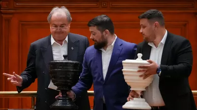 Staff members carry the voting urns at the end of a vote of confidence for Romanian Prime Minister designate Adrian Vestea and the new government team during a joint parliament session in Bucharest, Romania, Monday, June 22, 2026. (AP Photo/Vadim Ghirda)