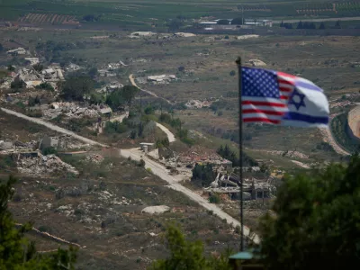 Israeli and U.S. flags stand against a backdrop of destroyed buildings in southern Lebanon, as seen from northern Israel, Sunday, June 21, 2026. (AP Photo/Ohad Zwigenberg) / Foto: Ohad Zwigenberg