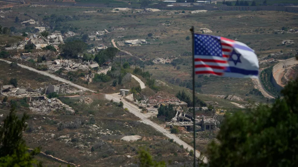 Israeli and U.S. flags stand against a backdrop of destroyed buildings in southern Lebanon, as seen from northern Israel, Sunday, June 21, 2026. (AP Photo/Ohad Zwigenberg) / Foto: Ohad Zwigenberg