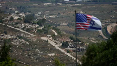 Israeli and U.S. flags stand against a backdrop of destroyed buildings in southern Lebanon, as seen from northern Israel, Sunday, June 21, 2026. (AP Photo/Ohad Zwigenberg) / Foto: Ohad Zwigenberg