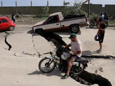 A man sits on a bike on a damaged road after earthquakes hit the country, in La Guaira, Venezuela, June 25, 2026. REUTERS/Gaby Oraa   TPX IMAGES OF THE DAY