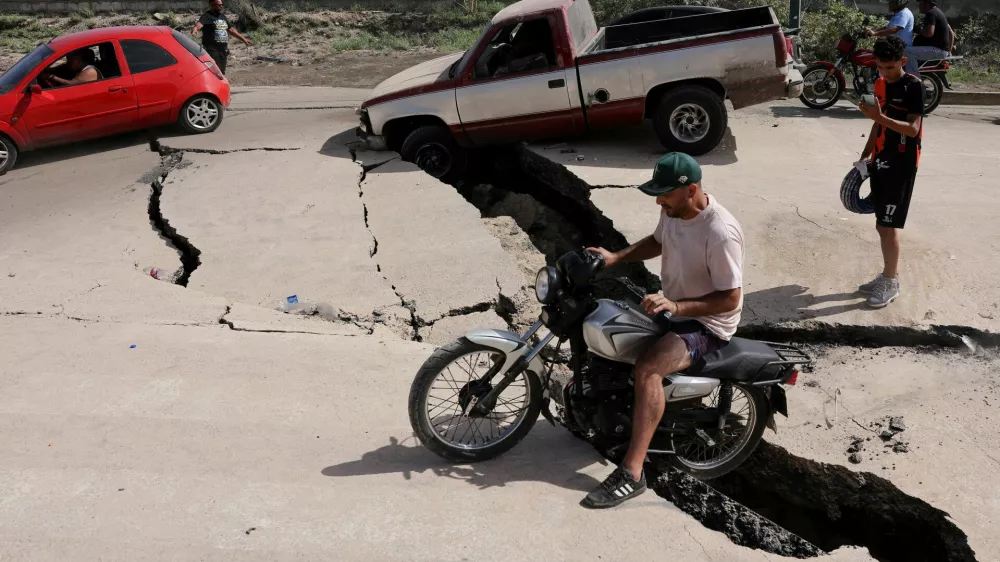 A man sits on a bike on a damaged road after earthquakes hit the country, in La Guaira, Venezuela, June 25, 2026. REUTERS/Gaby Oraa   TPX IMAGES OF THE DAY