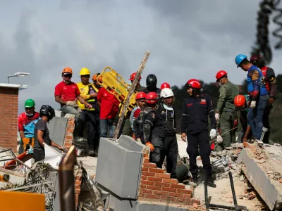 People stand atop the rubble of a collapsed building as they search for casualties amidst it, in the aftermath of earthquakes in Caracas, Venezuela, June 25, 2026. REUTERS/Leonardo Fernandez Viloria