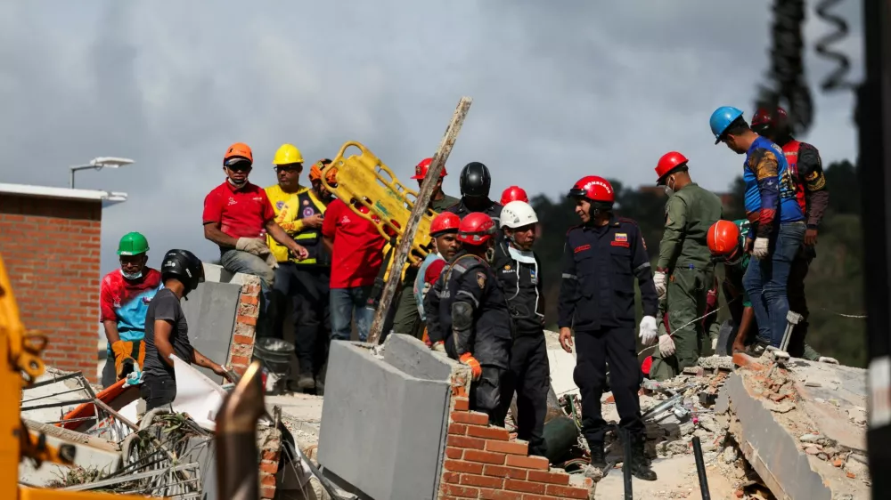 People stand atop the rubble of a collapsed building as they search for casualties amidst it, in the aftermath of earthquakes in Caracas, Venezuela, June 25, 2026. REUTERS/Leonardo Fernandez Viloria