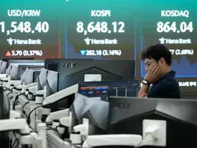 A currency trader watches monitors near a screen showing the Korea Composite Stock Price Index (KOSPI) and the foreign exchange rate between U.S. dollar and South Korean won at the foreign exchange dealing room of the Hana Bank headquarters in Seoul, South Korea, Friday, June 26, 2026. (AP Photo/Ahn Young-joon)