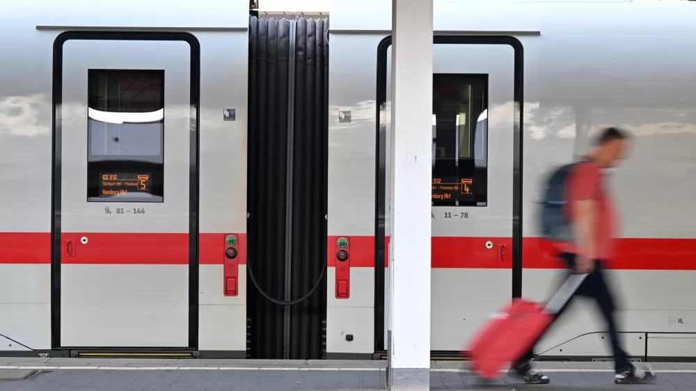 A passenger walks past an ICE train at Munich Central Station in Munich, Germany Wednesday, June 24, 2026, following the nationwide service disruption on the Deutsche Bahn network. (Peter Kneffel/dpa via AP)