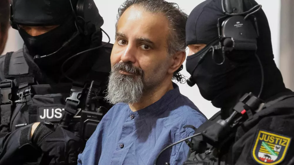 Suspect Taleb al-Abdulmohsen, a doctor from Saudi Arabia who faces charges of murder, attempted murder and dangerous interference with road traffic, looks on while being escorted by security officers as he attends his trial for the Magdeburg Christmas market attack, at a regional court in Magdeburg, Germany, June 26, 2026. REUTERS/Fabrizio Bensch
