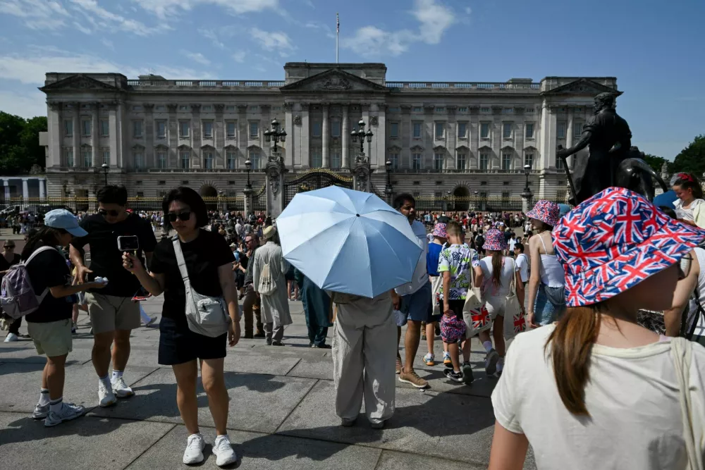 A person holds an umbrella to shield from the sun outside Buckingham Palace after it was announced that Britain's King Charles will not live there after its 10-year refurbishment finishes next year, amid a heatwave in London, Britain, June 26, 2026. REUTERS/Jaimi Joy   TPX IMAGES OF THE DAY