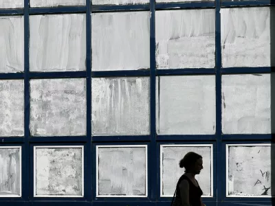 A woman walks past the public school Marie-Anne du Boccage with windows coated in Blanc de Meudon, a chalk-based powder applied by parents to protect their children from the heat in Nantes, during a heatwave affecting a majority of the country, France, June 25, 2026. REUTERS/Stephane Mahe   TPX IMAGES OF THE DAY