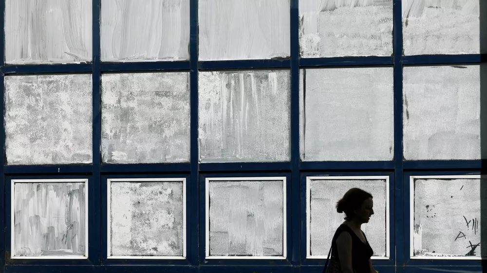 A woman walks past the public school Marie-Anne du Boccage with windows coated in Blanc de Meudon, a chalk-based powder applied by parents to protect their children from the heat in Nantes, during a heatwave affecting a majority of the country, France, June 25, 2026. REUTERS/Stephane Mahe   TPX IMAGES OF THE DAY