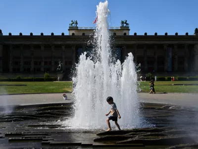 A child cool off in a fountain in front of Berlin Cathedral as temperature rise in Berlin, Germany, during a summer heat wave, Friday, June 24, 2026. (AP Photo/Ebrahim Noroozi)