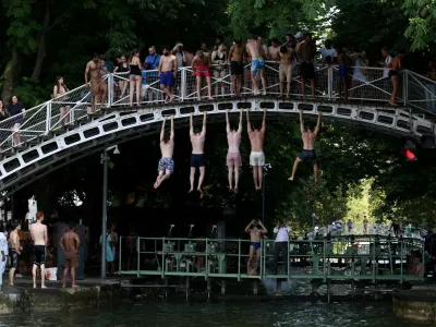 People hang from a bridge above the Canal Saint-Martin after public swimming was permitted in certain areas due to high temperatures amid a heatwave in Paris, France, June 26, 2026. REUTERS/Tom Nicholson   TPX IMAGES OF THE DAY / Foto: Tom Nicholson
