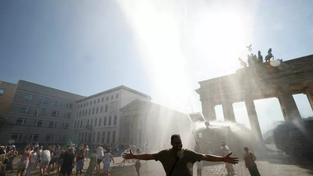People enjoy the water sprayed by a police water cannon at the Brandenburg Gate during the ongoing heatwave in Berlin, Germany, June 27, 2026. REUTERS/Axel Schmidt